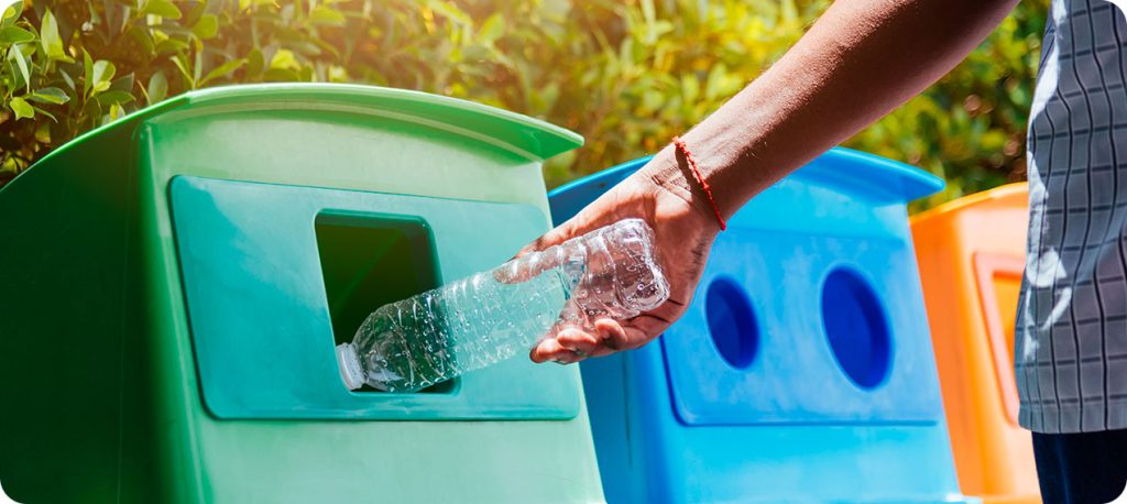 Pessoa jogando garrafa de plástico transparente no lixo reciclável.